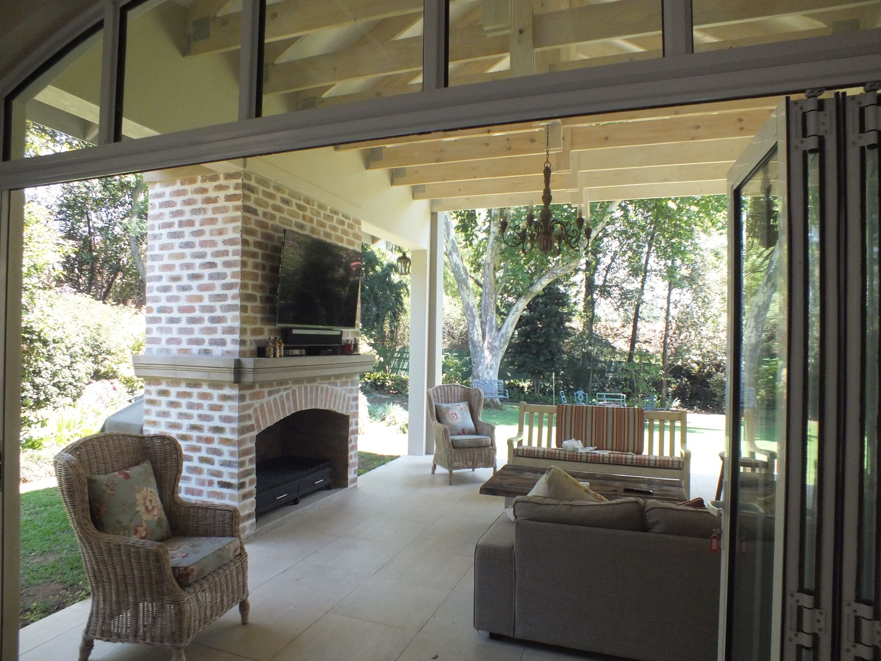 Interior of the Atholl living pavilion — brick fireplace, open truss and folding doors to the garden