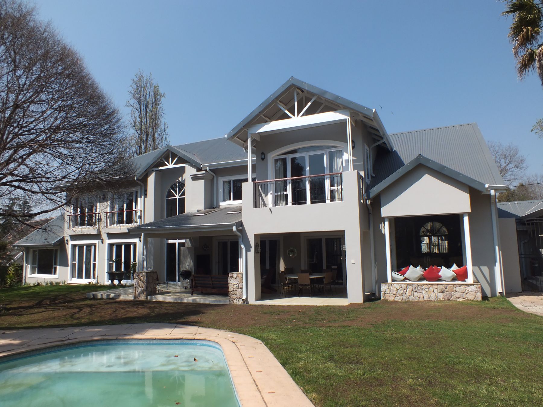 Double-storey Bryanston house after alteration, with balcony gable and pool