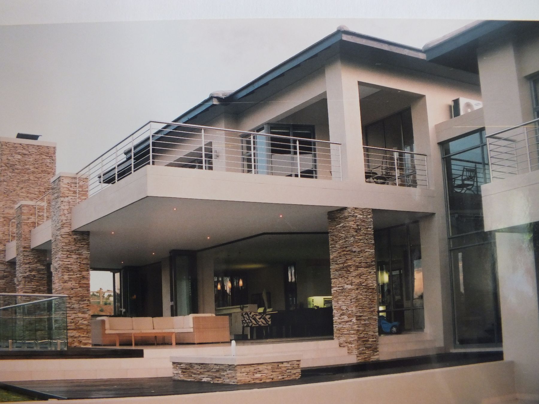 Contemporary new house at Blair Atholl with stone-clad piers, a cantilevered balcony and a reflecting pond