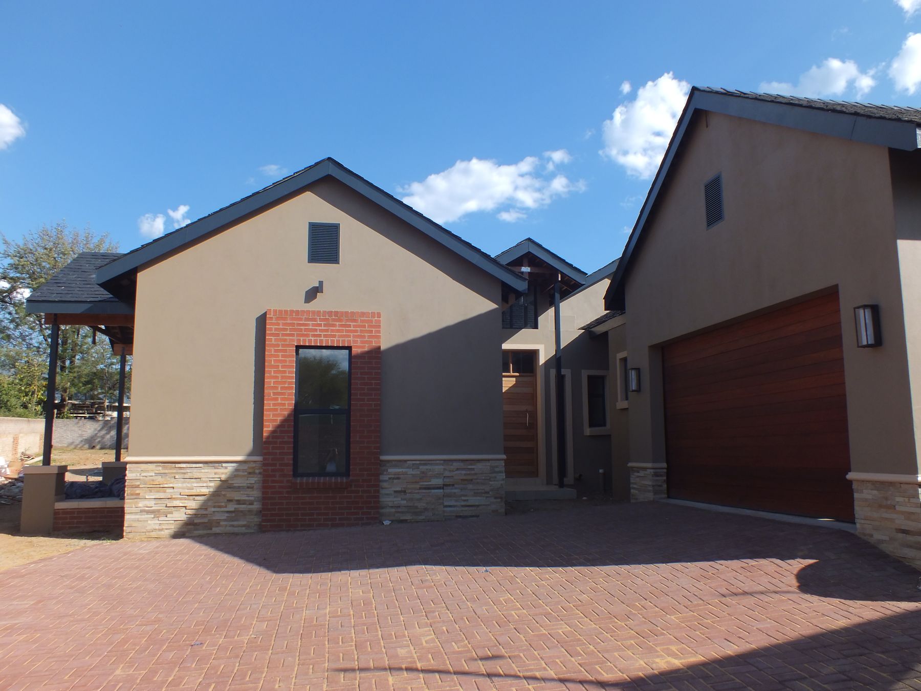New house in Fourways Gardens with face-brick accents, stone plinth and timber garage door