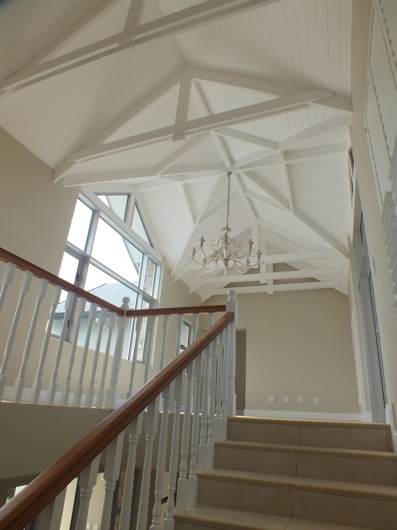 Stair hall beneath the open trusses — New house in Simbithi