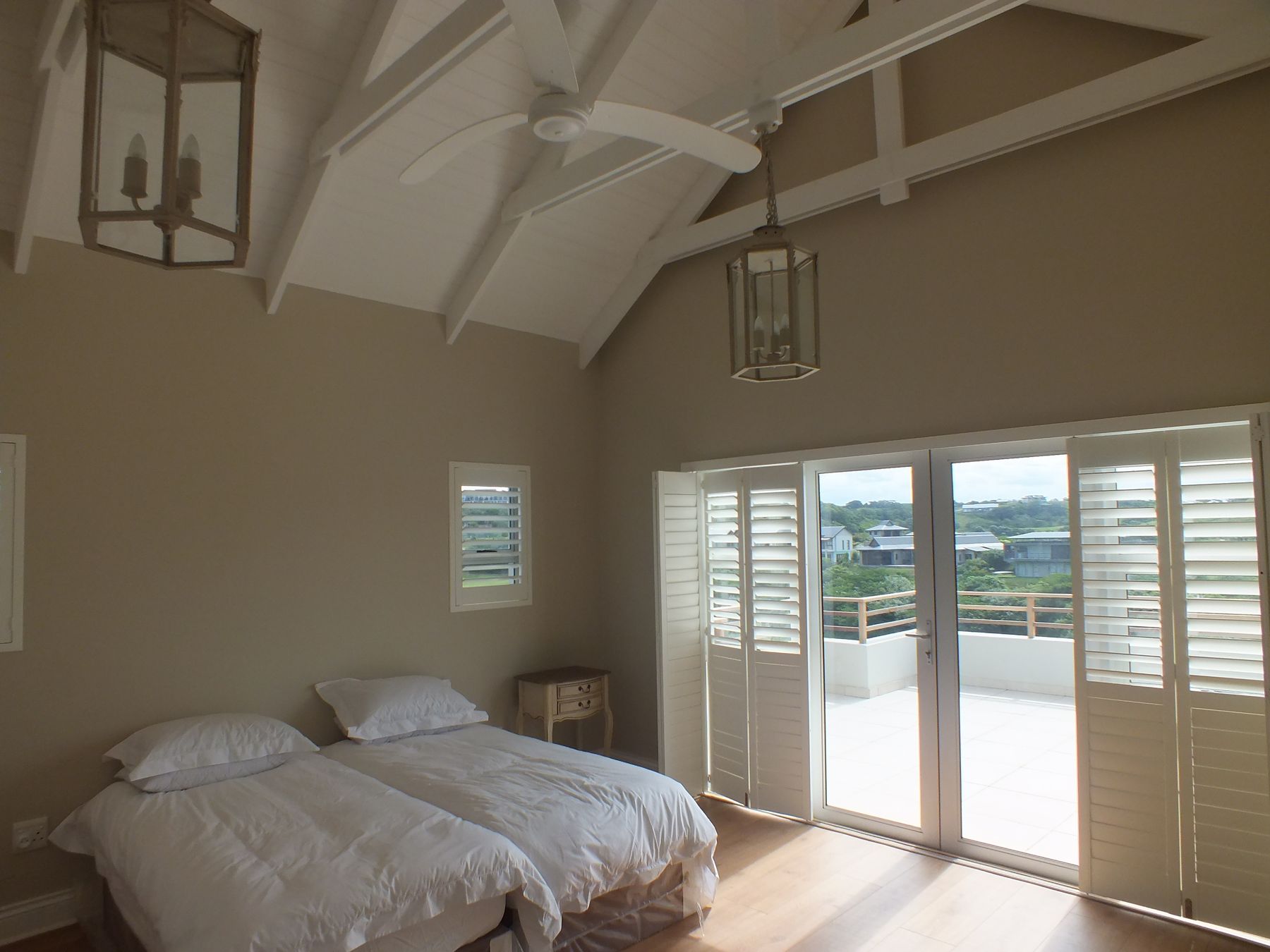 Bedroom opening to its terrace through shuttered doors — New house in Simbithi